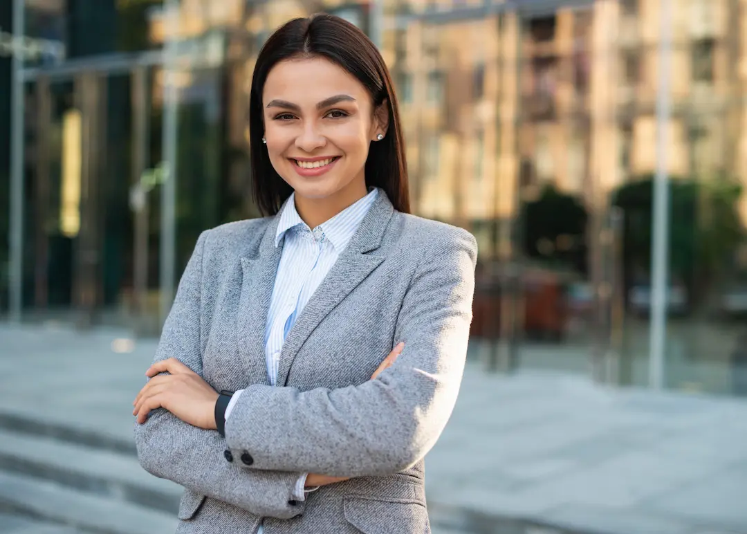 smiley-businesswoman-posing-outdoors-with-arms-crossed