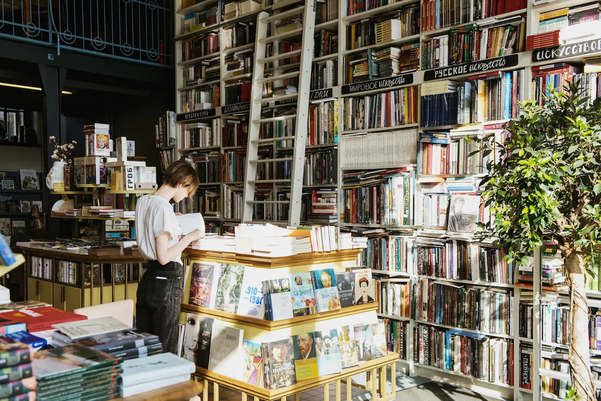 A person standing in library reading a book